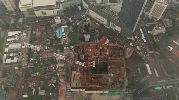 Aerial Tilting Shot Into Overhead of Tall Modern Skyscraper Under Construction with hole