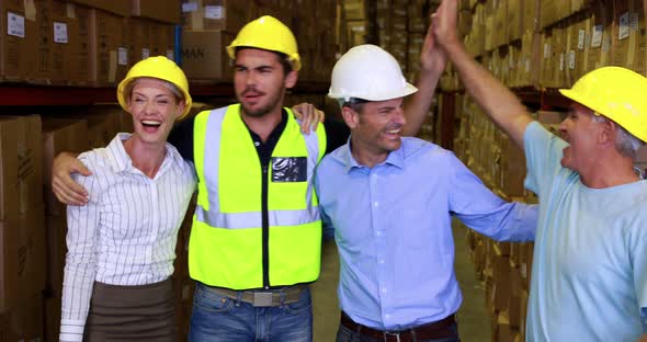 Warehouse team smiling and high fiving each other