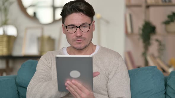 Middle Aged Man Using Digital Tablet at Home 