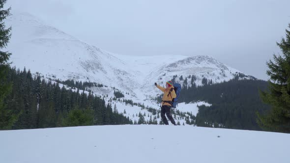 A Man with a Backpack Travels in the Mountains in Winter