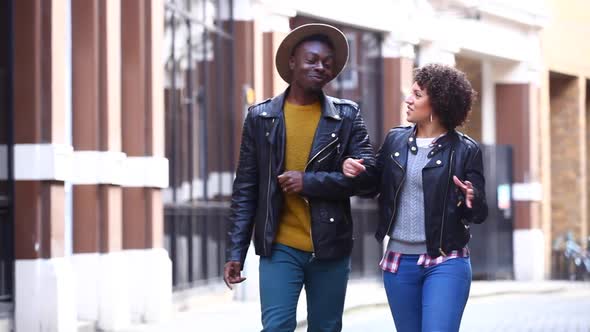 Mmultiracial couple walking embraced in London, talking and having fun togeth