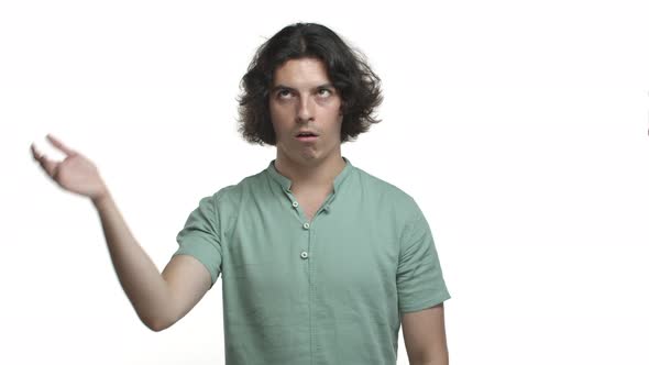 Attractive Hispanic Man with Long Dark Hair Wearing Green Shirt Looking Annoyed Rolling His Eyes and