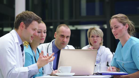 Team of doctors discussing over laptop in conference room