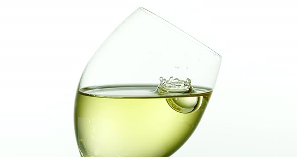 900046 Drop of White Wine falling into Glass, against White Background, Slow motion 4K