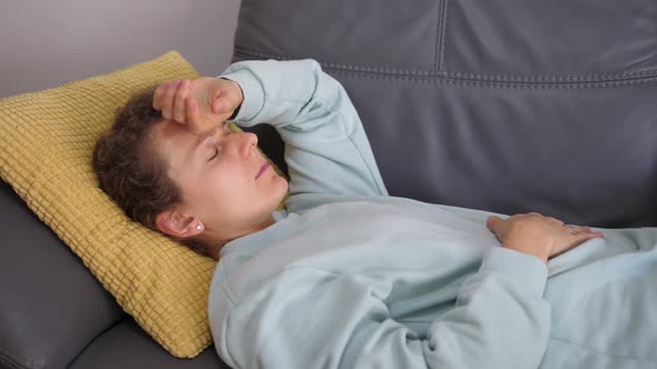 Young Woman on the Couch Touching Her Head Checking If She Has a High Temperature