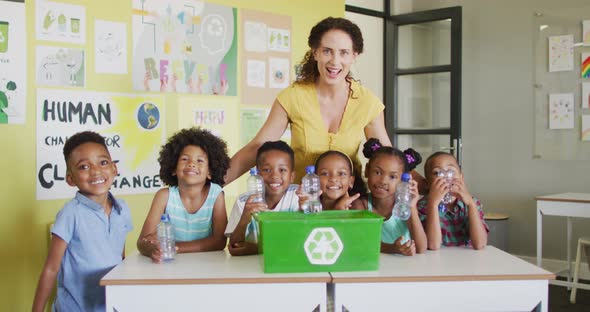 Video of happy caucasian female teacher and class of diverse pupils studying ecology in classroom