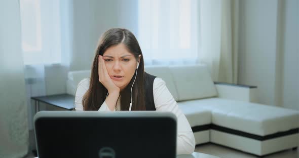 Long Haired Student in White Headphones Looks Into Laptop