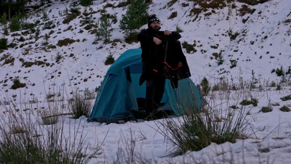 Hiker, arriving at tent, in the winter mountains