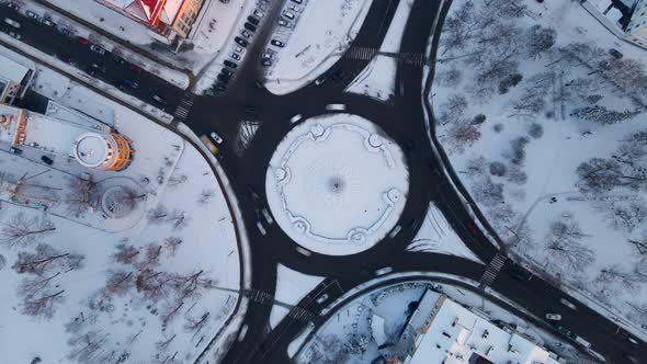 Aerial View of Roundabout Road with Circular Cars in Snow Covered Small European City at Winter Day