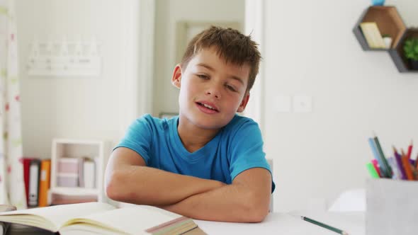 Portrait of caucasian boy with arms crossed smiling looking at the camera at home