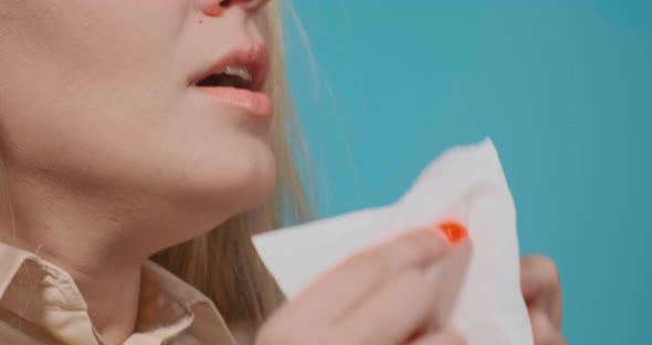 Young Woman with Long Hair Sneezes Into White Paper Napkin