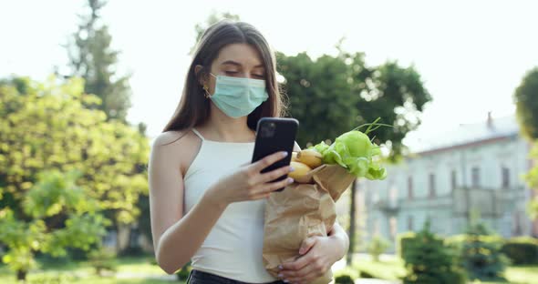 Woman Wearing Face Masks in Prevention of Coronavirus During Quarantine Using the Mobile Phone