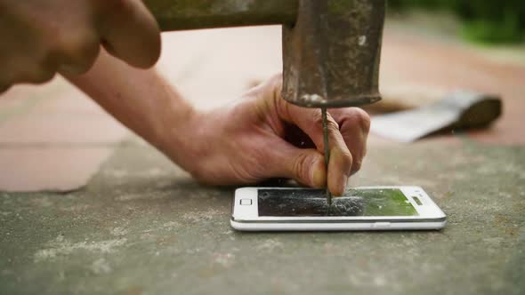 A Man Hammers a Nail Into the Phone on the Concrete Ground in Slow Motion