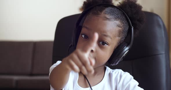 Portrait of Small Emotional African Girl 5 -7 Years Old Sits at Table at Home in Front of Computer