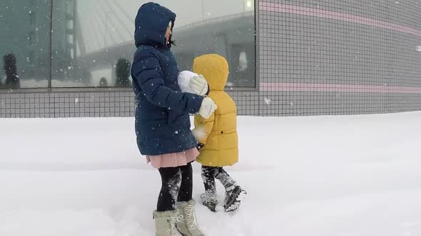 Asian Children Playing Under Snow Fall Together