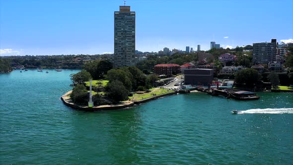 Drone tracks around Blues Point Reserve on Sydney Harbour with North Sydney skyscrapers in the backg