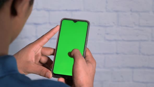Back View of Man Holding Smart Phone with Green Screen 