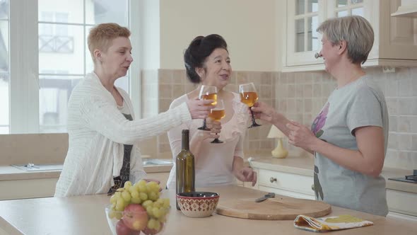 Three Positive Mature Women Communicating at Home Near Modern Table in the Kitchen