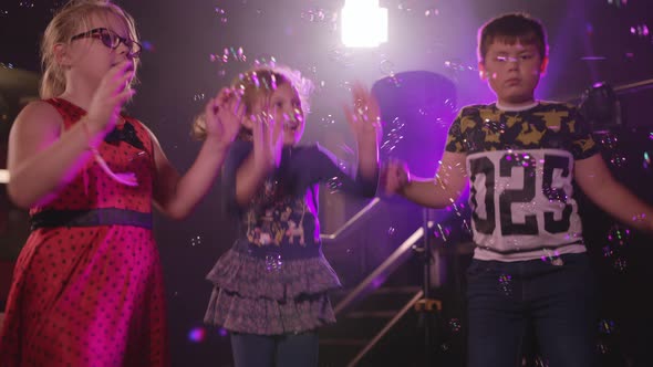 Kids Dancing at a Children's Party with Bubble Machine blowing Bubbles in to Air.