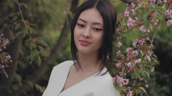 Asian Woman Outdoors on Spring Against Flower Blossom
