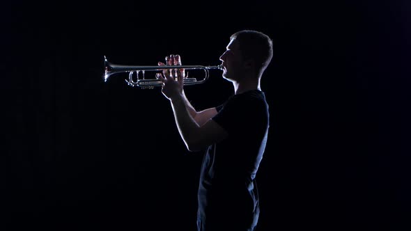 Man Trumpeter Blows the Motif in Wind Instrument. Black Studio