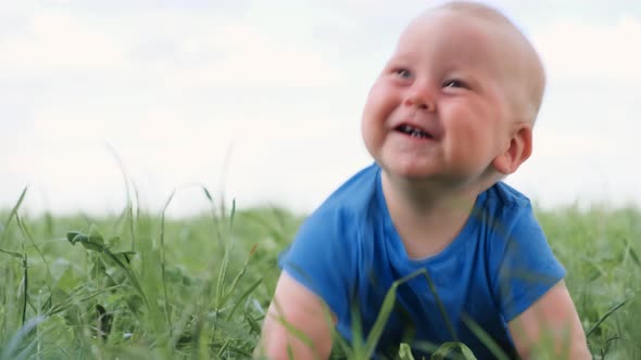 Baby Sitting Crawling on Green Grass and Smiling Broadly