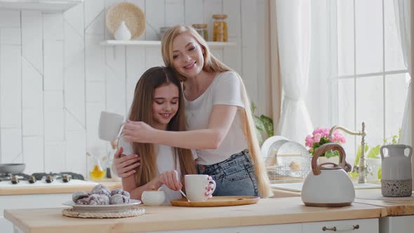 Adult Woman with Long Hair Loving Mother and Teenager Girl Daughter Schoolgirl Drinking Hot Tea in