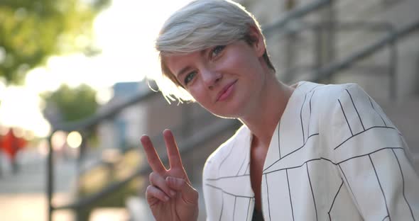 Beautiful short haired blonde caucasian girl women giving peace sign and hang loose with sweet kind