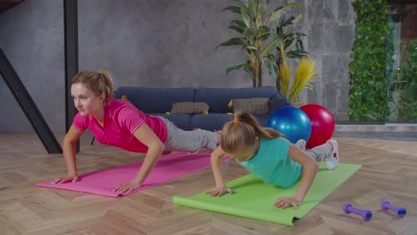 Sporty Fit Mom and Girl Doing Push Ups Together at Home