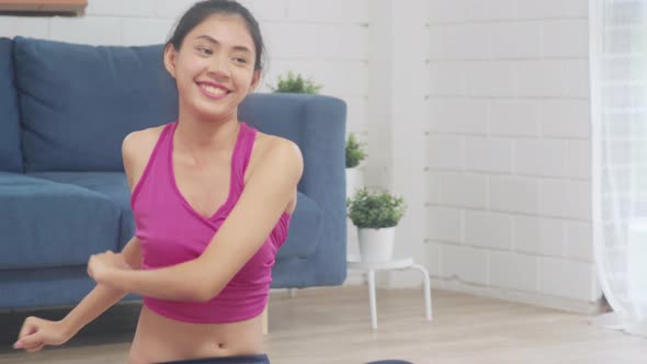 Young Asian woman practicing yoga in living room.