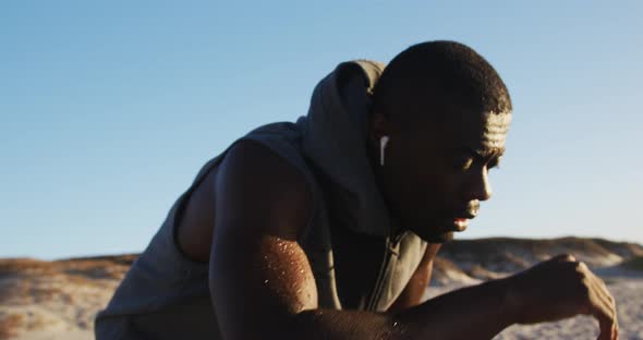 Focused african american man taking break in exercise outdoors by seaside
