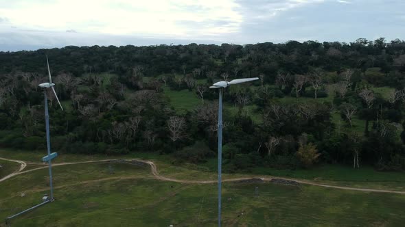 Aerial view of a wind farm situated on a mountain top near the coastline of a tropical island in the