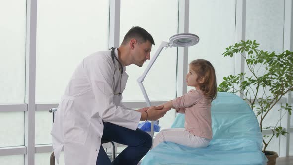 A Caring Doctor Examines the Throat of a Little Girl Using a Special Device