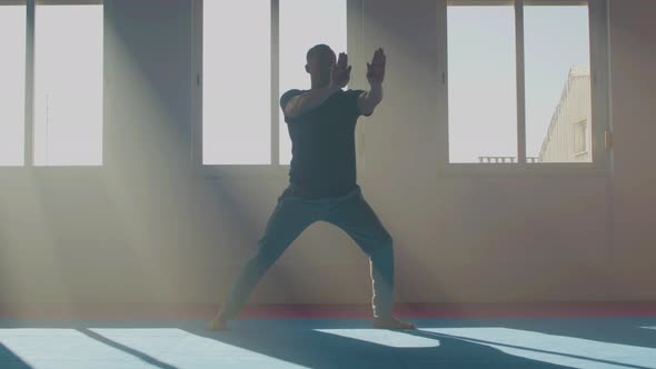 Concentrated Man Practicing Tai Chi in Sunlight Indoor