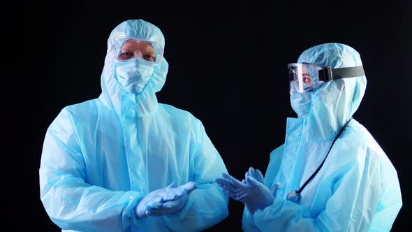 Two Medical Workers, Doctor or Nurse, in Special Protective Suits, Masks, Goggles Are Clapping