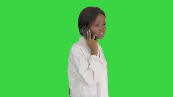 African American Female Doctor Talking on the Phone While Walking on a Green Screen, Chroma Key.