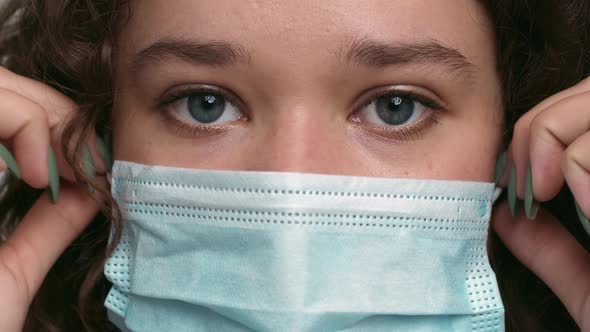 Close Up Portrait of Young Woman Taking Off Protective Medical Mask Looking at Camera Slow Motion