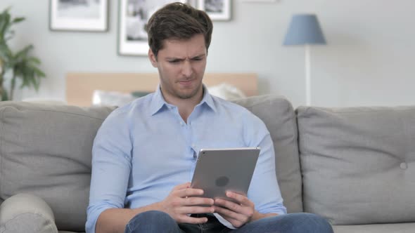 Handsome Young Man in Shock by Loss while Using Tablet