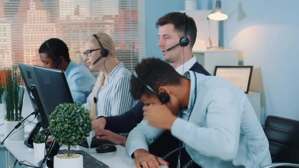 Medium Shot of Black Customer Support Operator Falling Asleep on His Table in Call Center