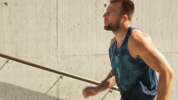 Young Man in Earphones Running Upstairs Outdoors