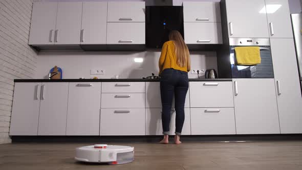 Woman Working in Home Kitchen While Robot Cleaning