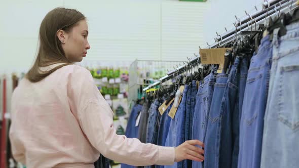 Woman in Second Hand Store Choosing Jeans