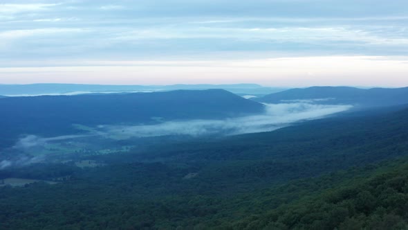 An aerial shot (dolly out) of Big Schloss and the Trout Run Valley at dawn in the summer, located on