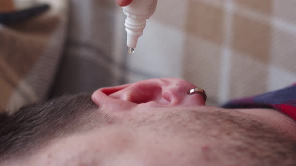 Closeup of Mans Ear in Which Medicine is Dropped From Bottle