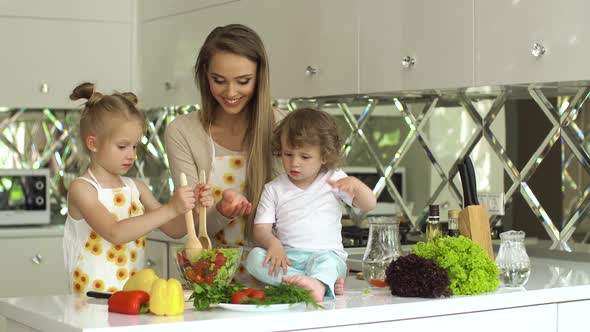 Woman With Kids Cooking Vegetables Salad At Kitchen