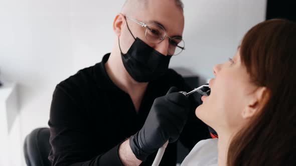 A Professional Dentist in a Protective Mask Works with a Patient in the Clinic