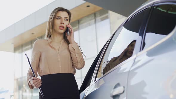 Confident Businesswoman Talking on Smartphone With Client Near Parked Car