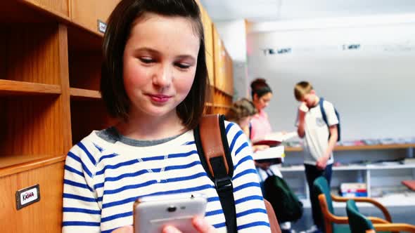 Smiling school girl using mobile phone in class room