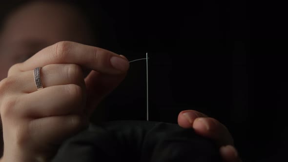 Slow motion shot of thread passing through sewing needle. woman sewing project by hand