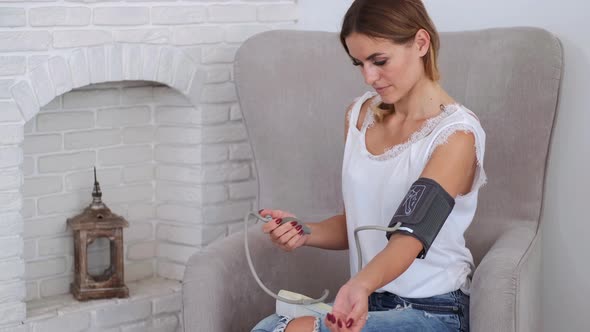 Woman Measuring Pressure with Stethoscope in Living Room